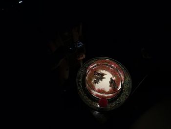 High angle view of man holding drink against black background