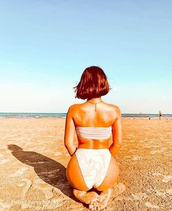 Rear view of woman sitting on beach