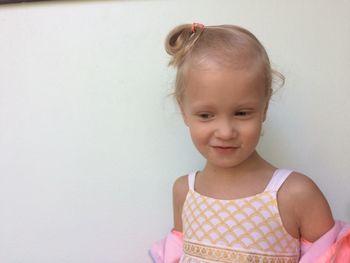 Close-up of girl standing against white wall