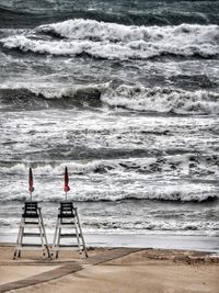 Deck chairs on beach against sky