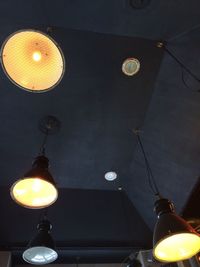 Low angle view of lit lamp hanging on ceiling