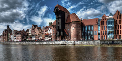 River by buildings against cloudy sky