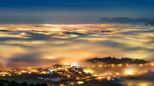 Aerial view of illuminated city against sky during sunset