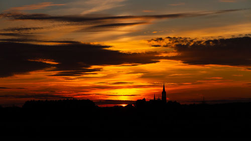 Silhouette landscape against dramatic sky during sunset