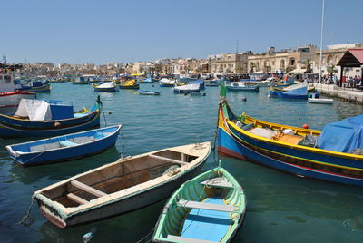 Boats moored on lake against clear sky in city