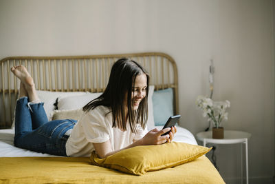 Man using mobile phone while sitting on bed