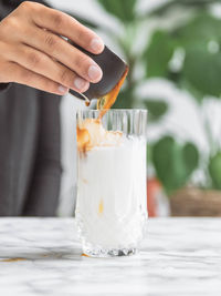 Close-up of hand holding drink on table