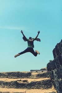 Low angle view of man jumping against sky