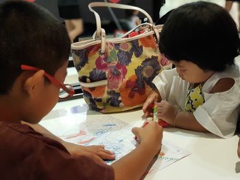 Boy with sister drawing on paper at table