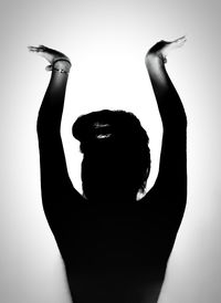 Silhouette woman with arms raised standing against white background