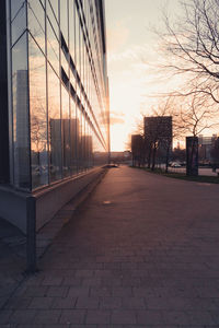 Footpath amidst buildings against sky during sunset