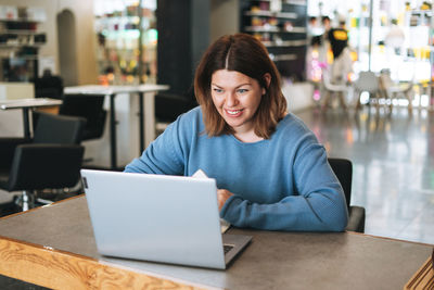 Beautiful stylish young woman plus size body positive using laptop at the beauty salon office