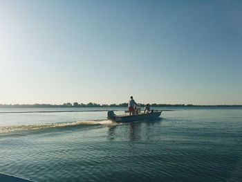 Men motorboating in river against clear sky