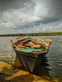 Fishing boat moored in lake against sky