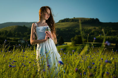 Smiling girl looking away while standing amidst flowers