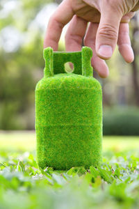 Close-up of hand holding green gas cylinder