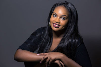 Close-up portrait of young woman against gray background