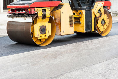 Close-up of yellow machinery on road at construction site