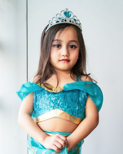 Portrait of cute girl dressing as arabian princess standing against wall