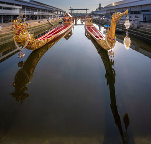 Reflection of bridge in canal against sky in city