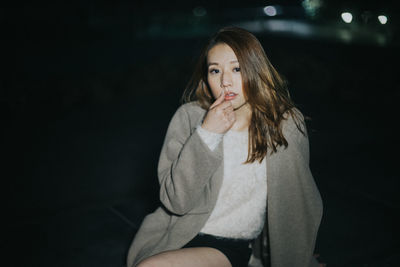 Portrait of woman sitting outdoors at night