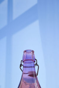 Close-up of glass bottle against blue wall