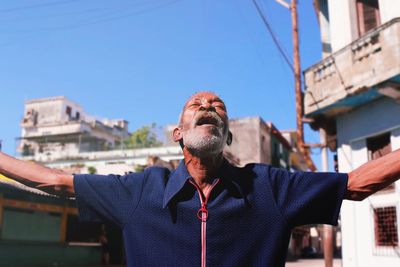 Low angle view of man standing against blue sky