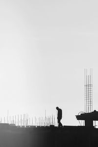 Silhouette man standing in city against clear sky