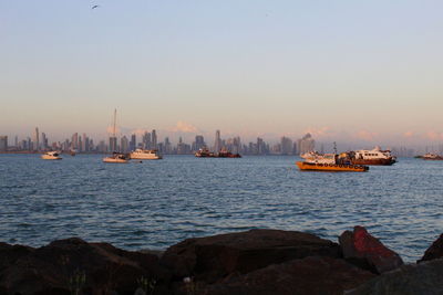 Boats sailing in sea against clear sky