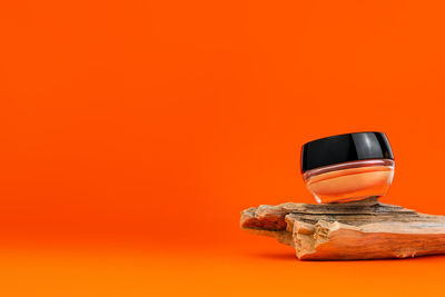 Cosmetic cream tonal foundation jar mockup wood podium orange background. balancing makeup product 