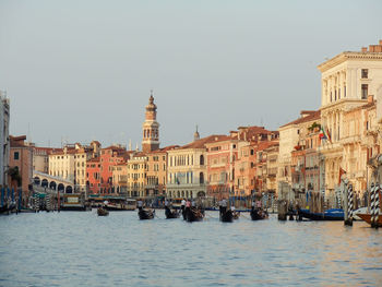 Gondolas on canal amidst buildings in city