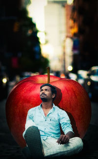 Portrait of young man sitting on street in city