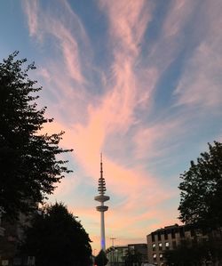 Low angle view of communications tower against cloudy sky