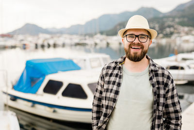 Portrait of young man standing against boat