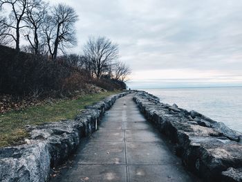 Footpath by sea against sky