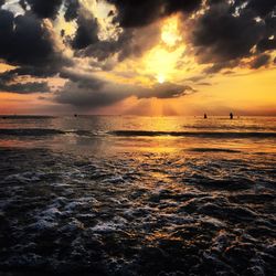 Scenic view of sea against dramatic sky during sunset