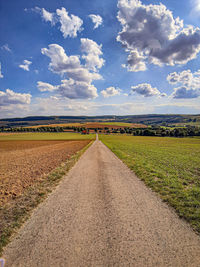 Road amidst field against sky