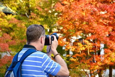 Full length portrait of man photographing during autumn