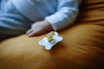 Midsection of baby boy pacifier on bed at home