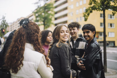 Portrait of smiling girl standing with male and female friends at street