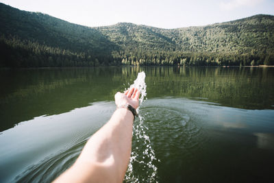 Low section of person on lake against mountain