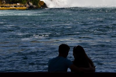 Rear view of men sitting at beach