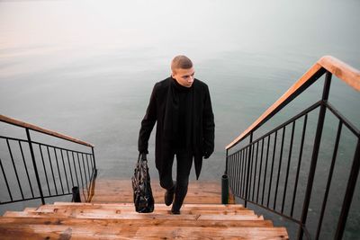 High angle view of man walking on steps against lake