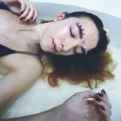 Woman with decorated face lying down in bathtub