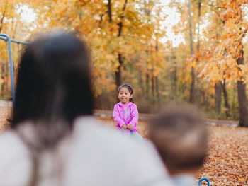 Mother and kids playing in park during autumn