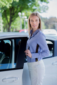 Portrait of woman standing by car