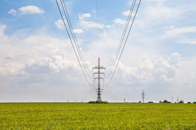 Low angle view of electricity pylon on field against sky