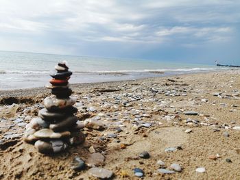 Stack of pebbles on beach against sky