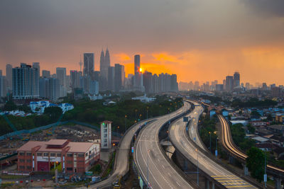 Distant view of petronas towers against sky during sunset in city