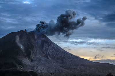 Low angle view of smoke emitting from mount sinabung against cloudy sky